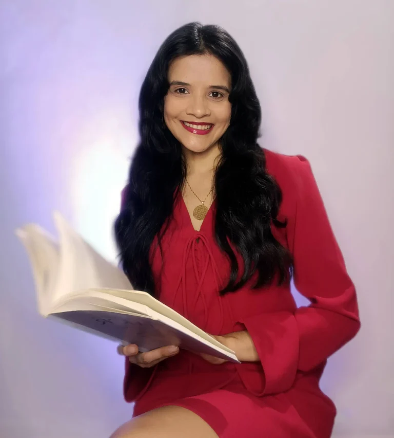 Jazmín González sosteniendo un libro, sonriendo y mirando a la cámara, sentada de lado