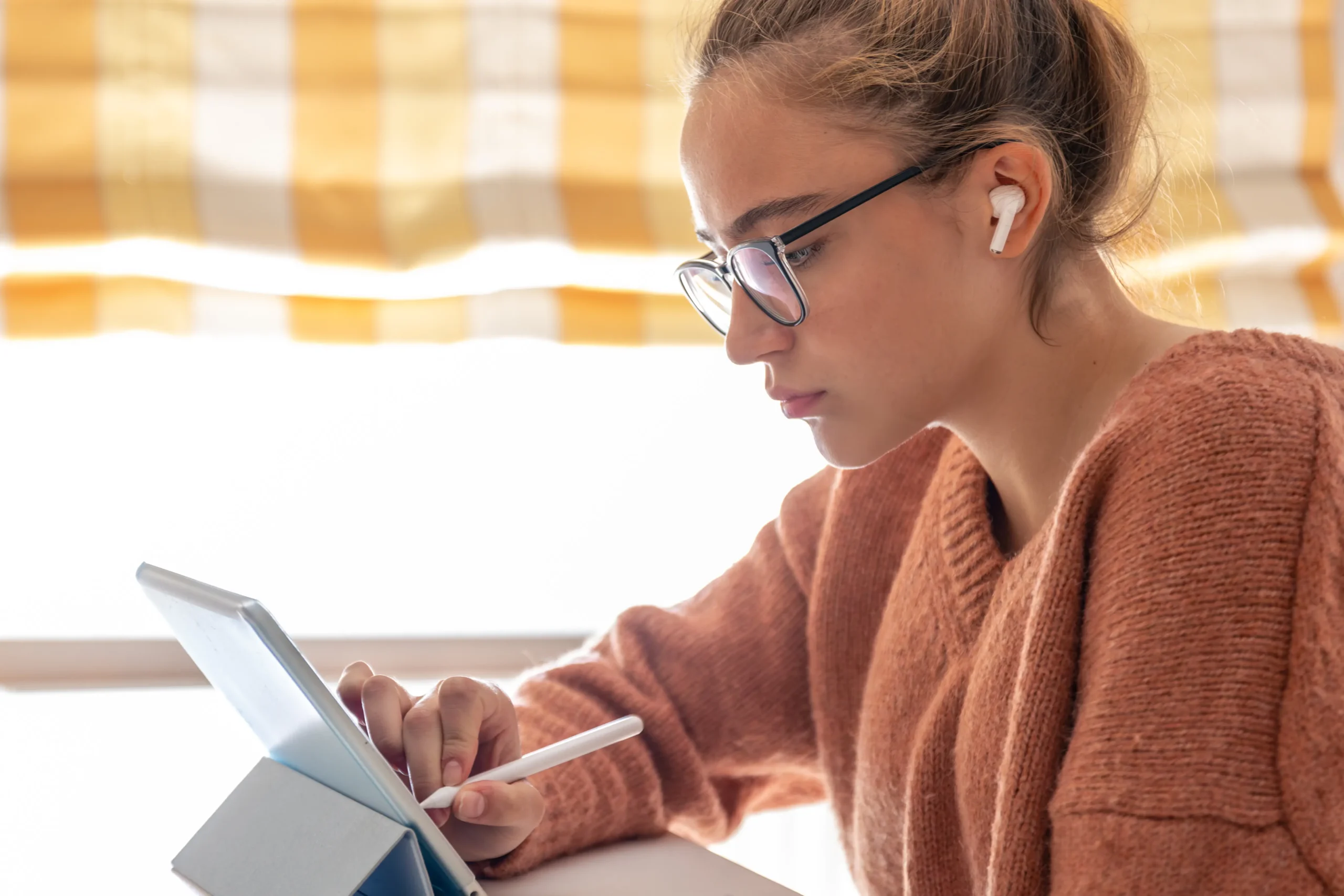 Mujer seria mirando una pantalla tipo iPad con auriculares, disfrutando de un audiolibro de la colección disponible
