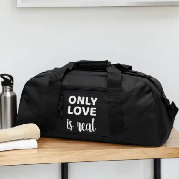 Bolso negro con diseño minimalista, lleva la frase 'Only love is real' en letras blancas, estilo tipografía elegante, artículo de merchandising de la Tienda Mente Uno disponible en Amazon, TeePublic y Spreadshirt